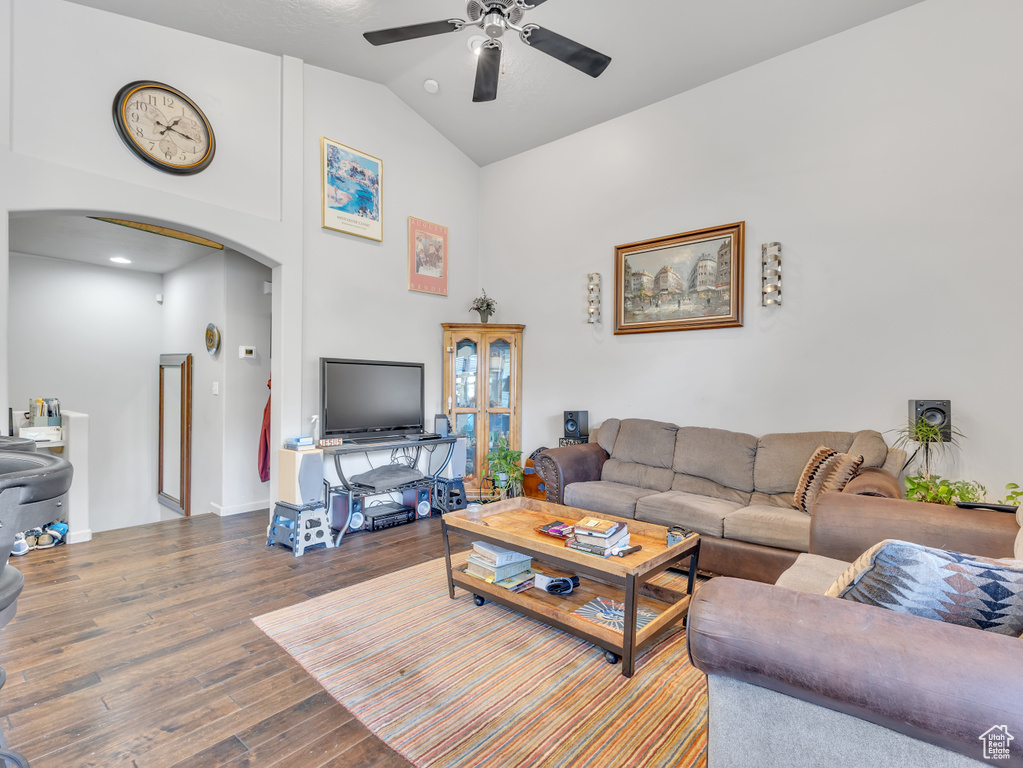 Living room featuring arched walkways, a ceiling fan, high vaulted ceiling, and wood finished floors