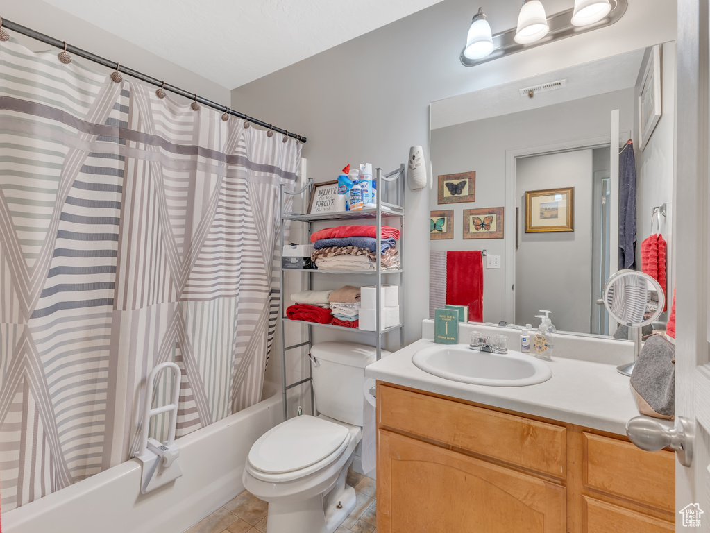 Bathroom featuring vanity, shower / bath combination with curtain, and tile patterned floors