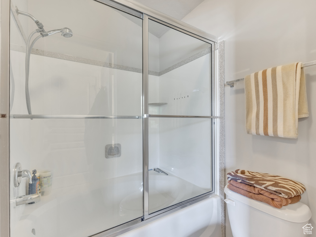 Bathroom with toilet and shower / bath combination with glass door
