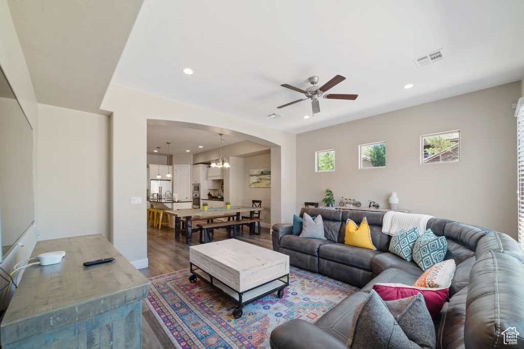 Living area featuring a ceiling fan, wood finished floors, arched walkways, recessed lighting, and a chandelier