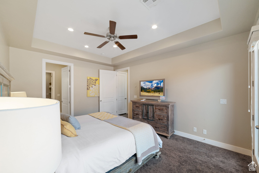 Bedroom with a tray ceiling, dark colored carpet, recessed lighting, and ceiling fan