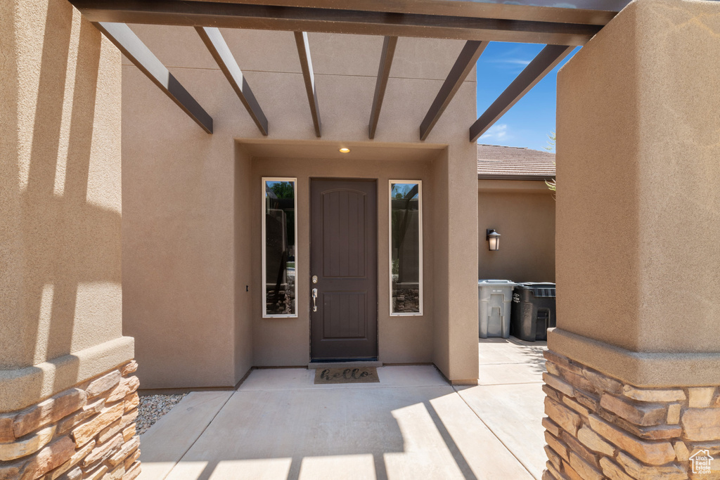 View of exterior entry featuring stucco siding and a patio