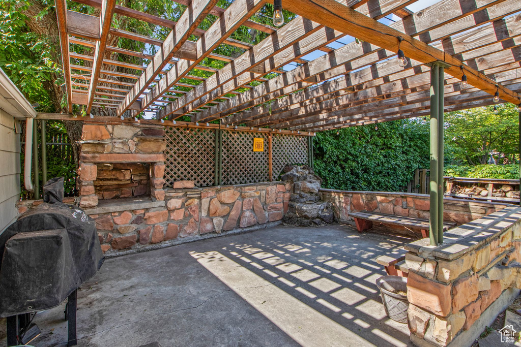 View of patio with area for grilling and a pergola