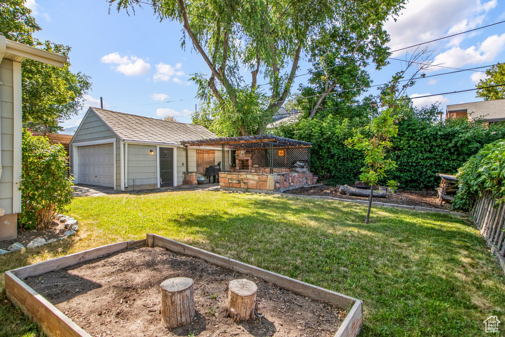 View of grassy yard featuring a garden, an outbuilding, and a garage