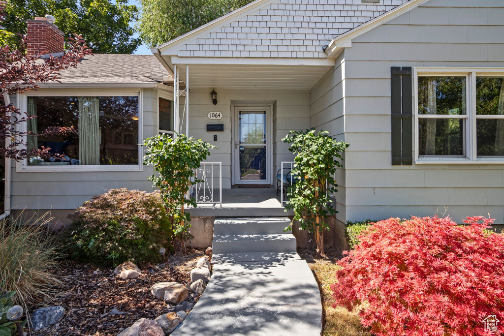 Doorway to property featuring covered porch and a chimney