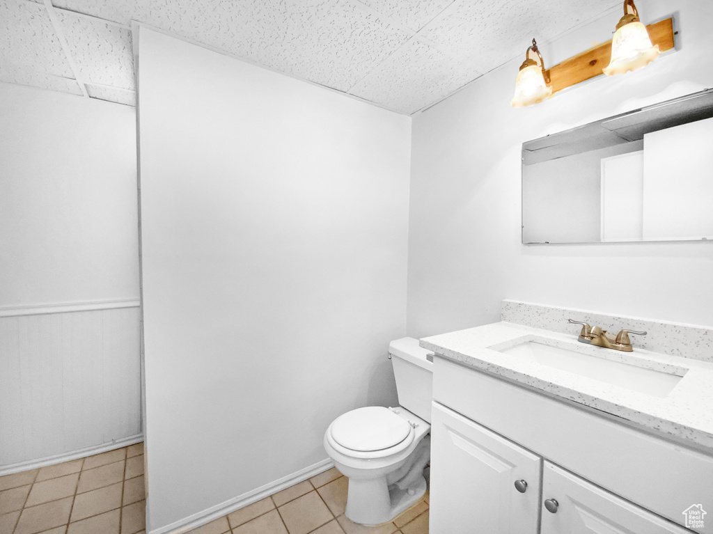 Half bathroom with vanity, tile patterned flooring, and a drop ceiling
