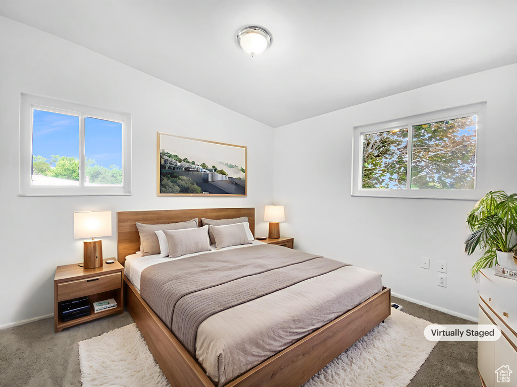 Carpeted bedroom featuring baseboards and lofted ceiling