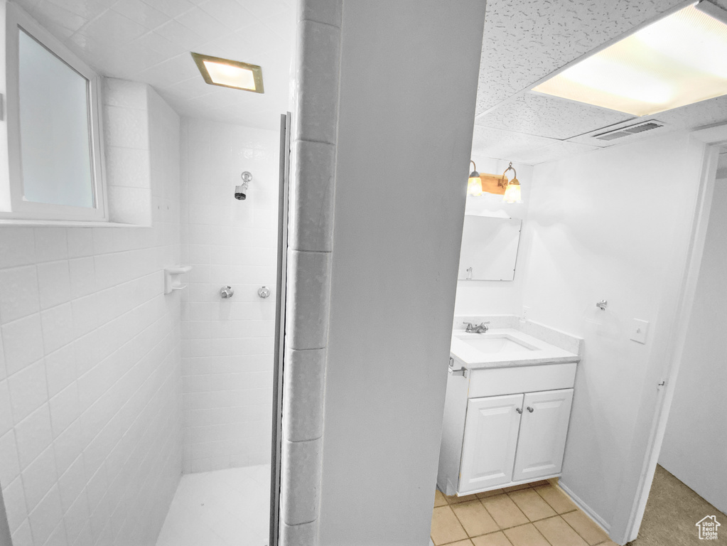 Bathroom with vanity, a stall shower, tile patterned floors, and a drop ceiling