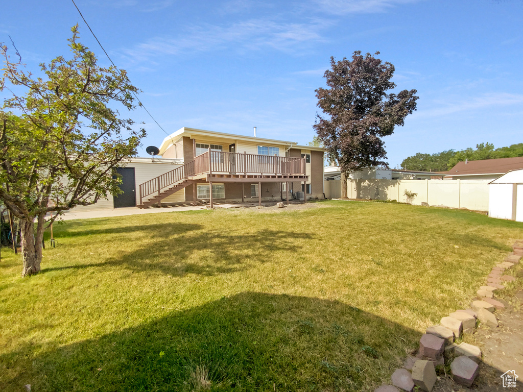 Back of property featuring a wooden deck, stairway, and a storage unit
