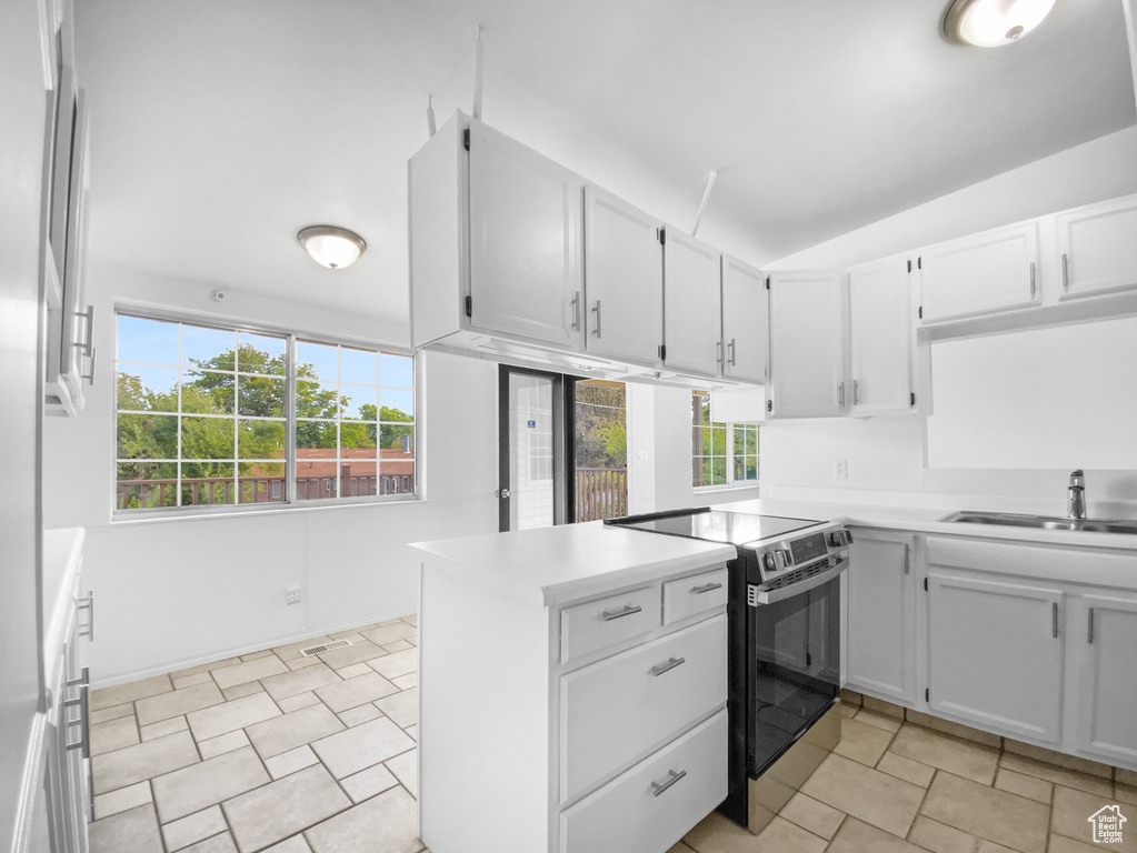 Kitchen with electric range, light countertops, white cabinets, a peninsula, and vaulted ceiling