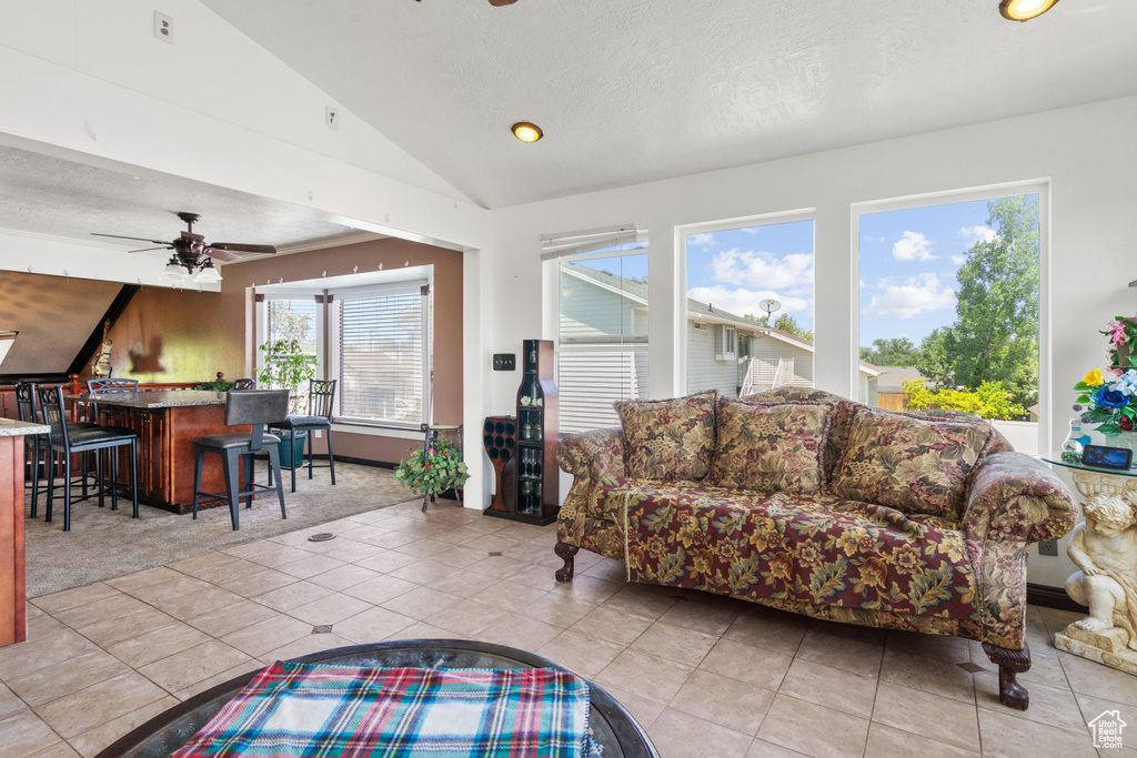 Tiled living room featuring lofted ceiling, bar area, ceiling fan, recessed lighting, and a textured ceiling