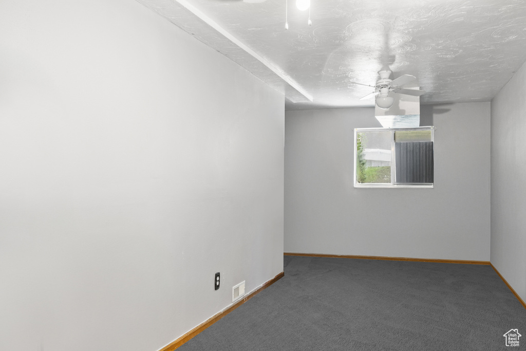 Carpeted empty room featuring a ceiling fan and a textured ceiling
