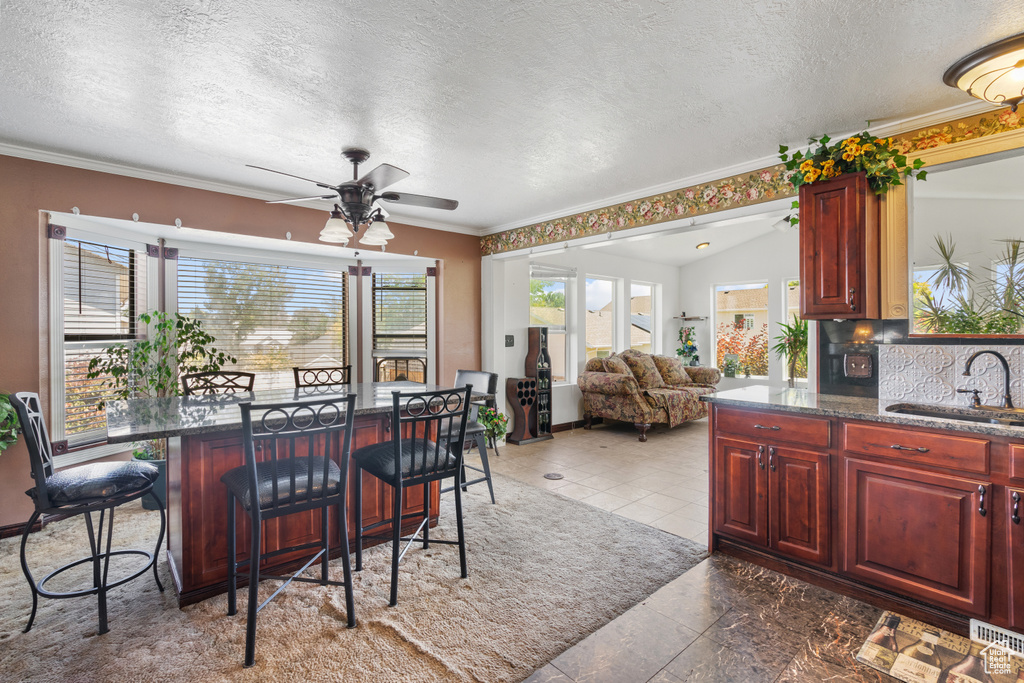 Dining space featuring a textured ceiling, a ceiling fan, ornamental molding, and a dry bar