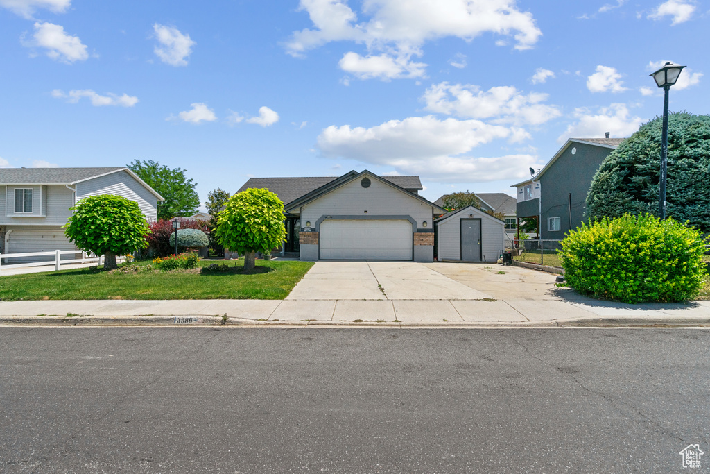 View of front facade with a shed, an attached garage, concrete driveway, and a residential view