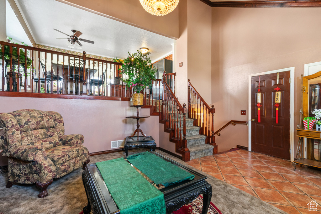 Living area with ceiling fan, tile patterned floors, a high ceiling, and crown molding
