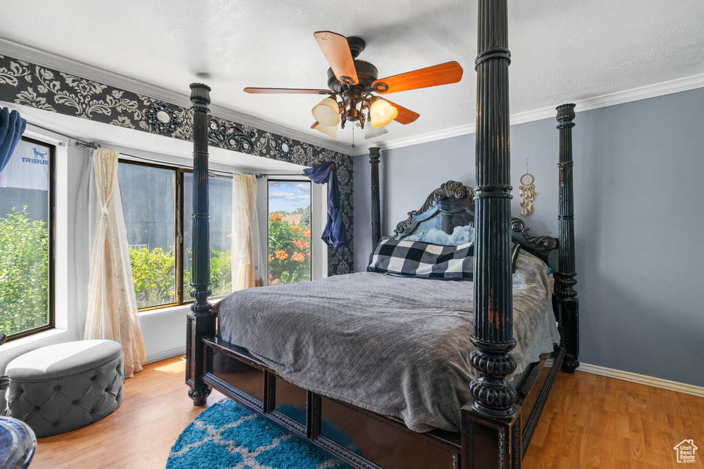 Bedroom featuring wood finished floors, ornamental molding, and a ceiling fan