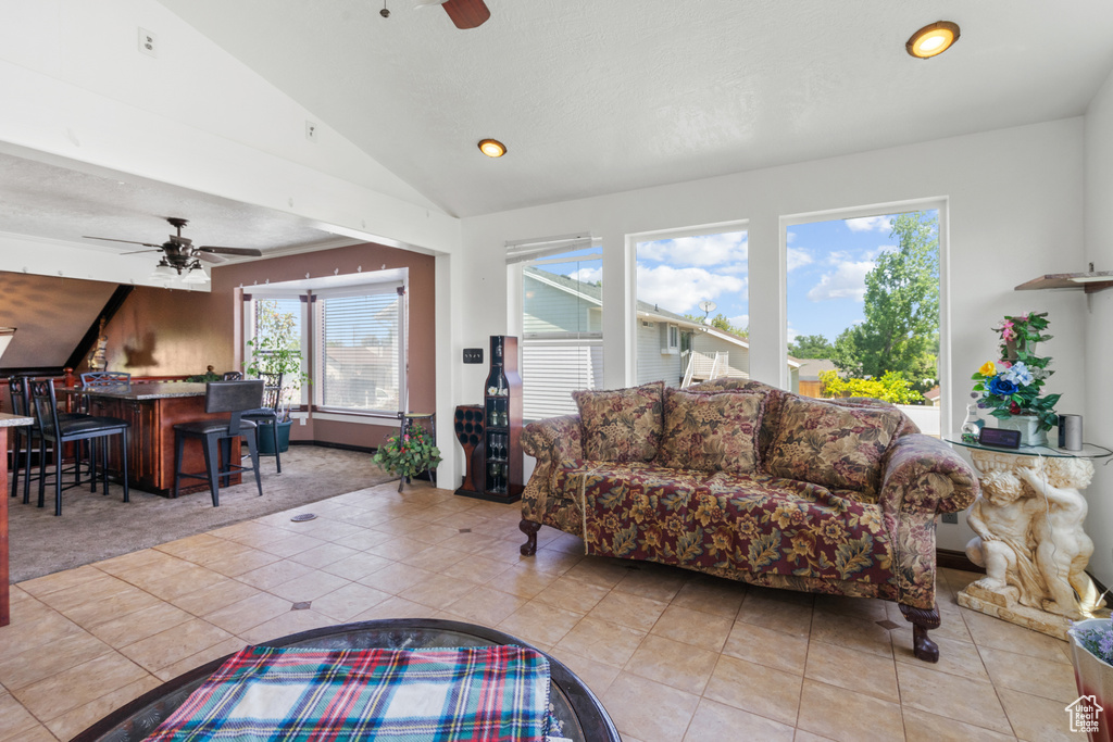 Living room featuring ceiling fan, light tile patterned floors, lofted ceiling, recessed lighting, and light carpet