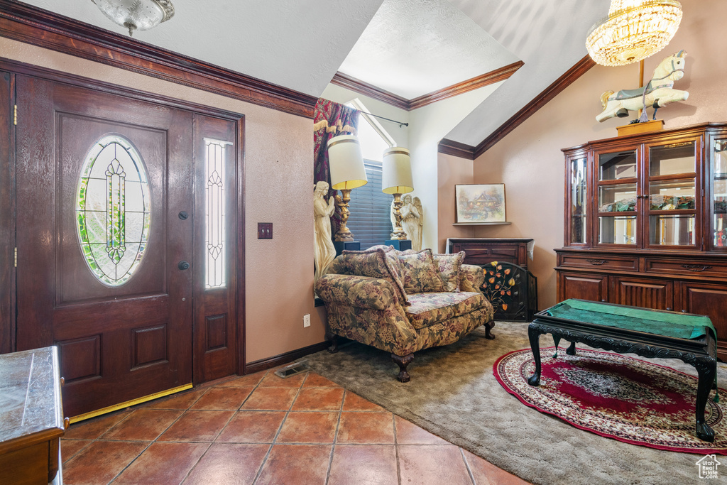 Tiled foyer entrance with vaulted ceiling and ornamental molding