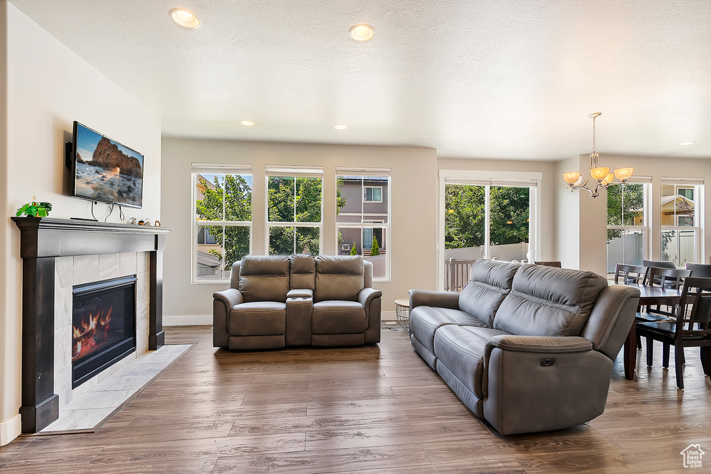 Living area featuring a chandelier, plenty of natural light, wood finished floors, a fireplace, and recessed lighting