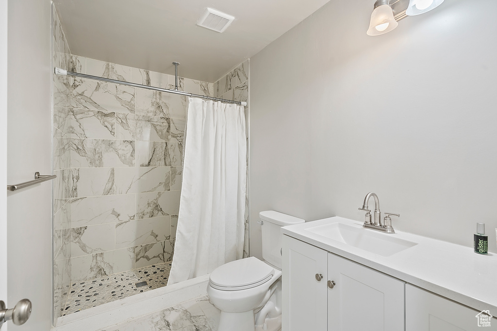 Bathroom featuring marble finish floors, a tile shower, and vanity