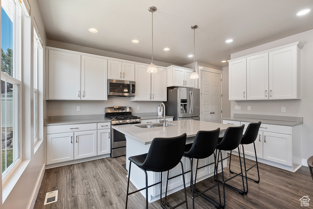 Kitchen with appliances with stainless steel finishes, plenty of natural light, wood finished floors, and recessed lighting