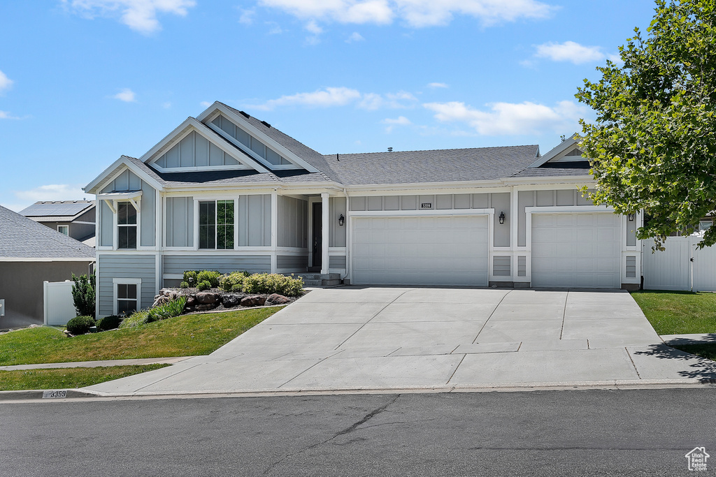View of front of property featuring board and batten siding, a garage, driveway, and a shingled roof