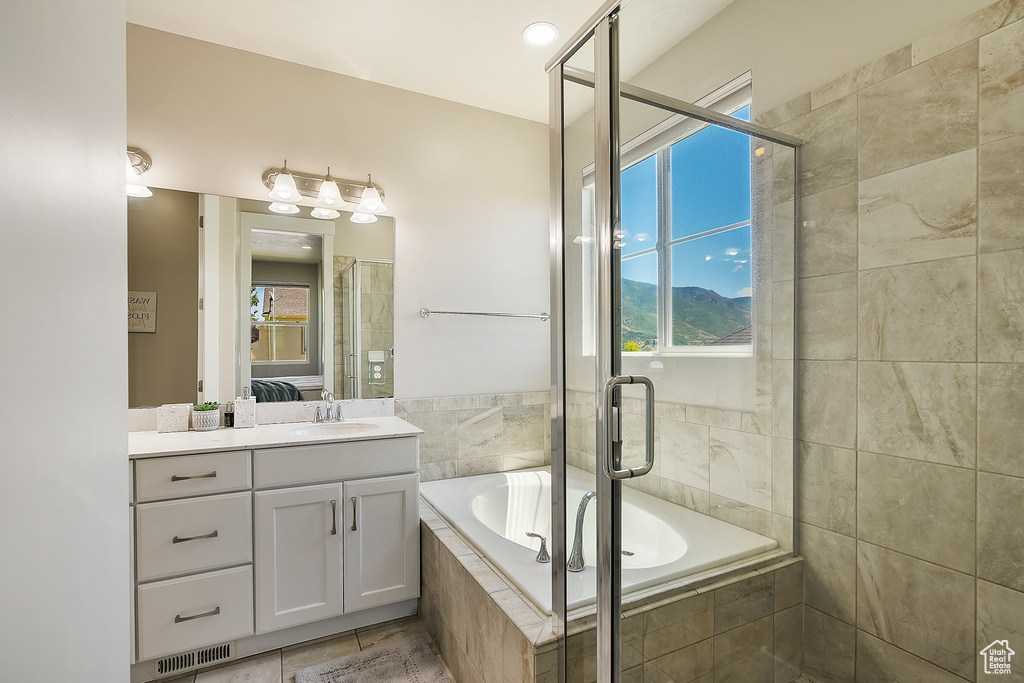 Full bathroom featuring vanity, a garden tub, plenty of natural light, and a shower stall