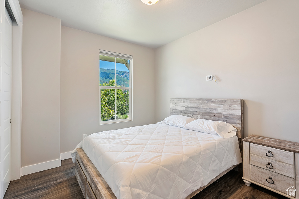 Bedroom with dark wood-type flooring and baseboards