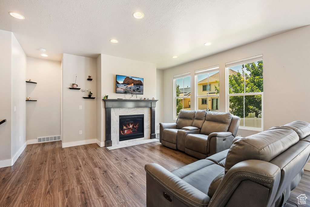 Living area featuring wood finished floors, a tiled fireplace, and recessed lighting
