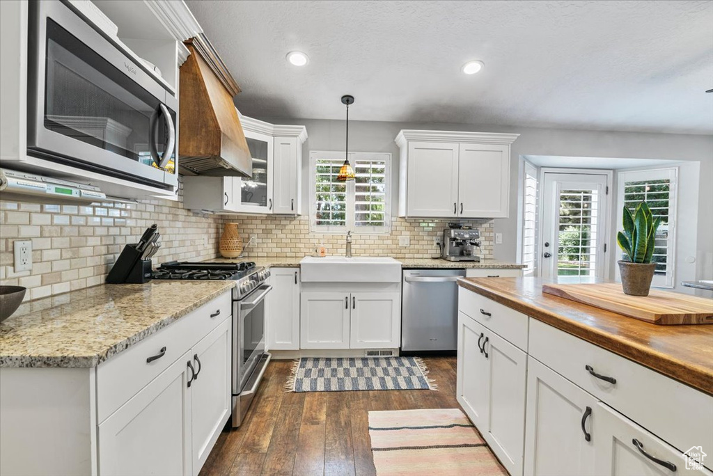 Kitchen with stainless steel appliances, dark wood-style floors, white cabinets, hanging light fixtures, and recessed lighting