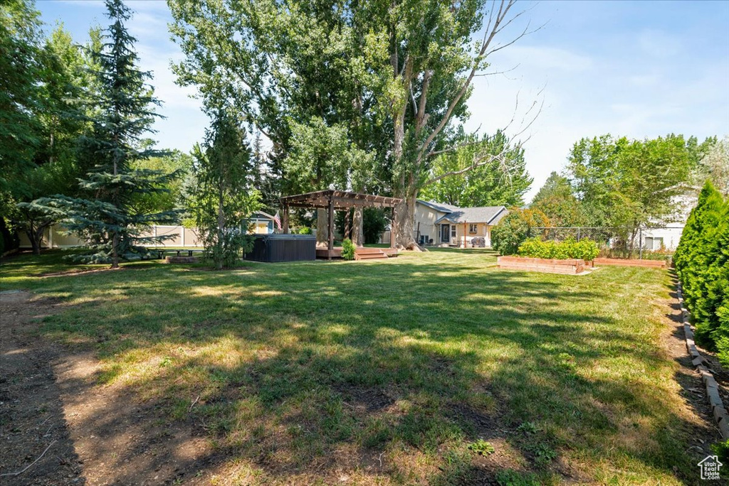 View of green lawn featuring a hot tub and a pergola