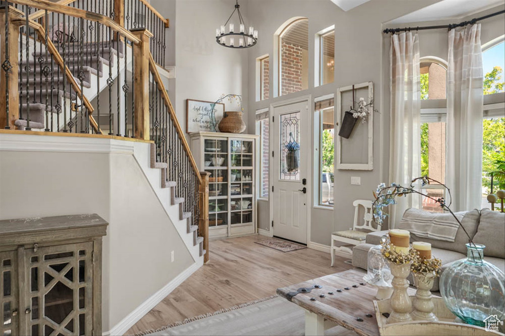 Foyer featuring wood finished floors, stairs, a chandelier, and a towering ceiling