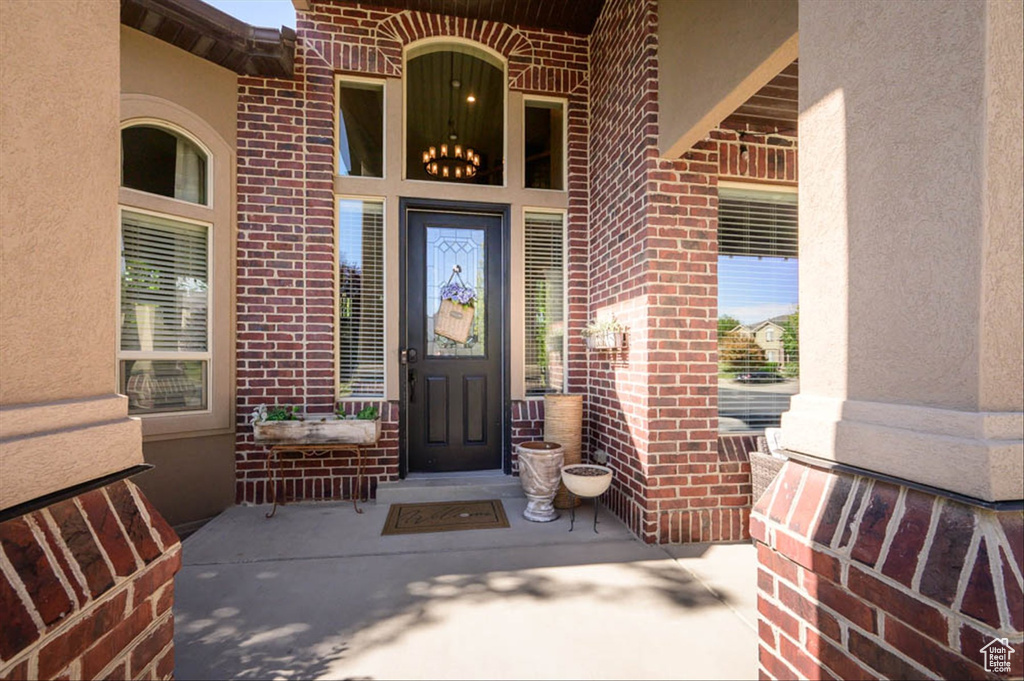 Doorway to property with brick siding, stucco siding, and a porch