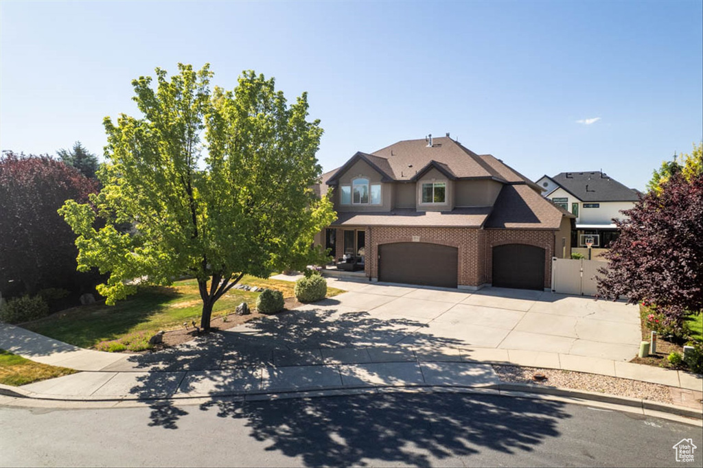 View of front of house featuring an attached garage, driveway, and brick siding
