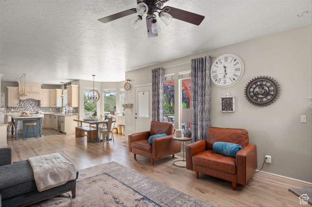 Living area featuring ceiling fan, light wood-style flooring, and a textured ceiling