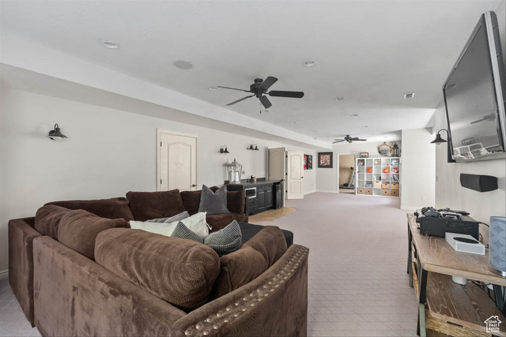 Carpeted living area with ceiling fan and baseboards