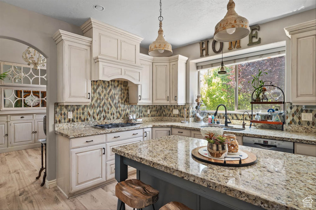 Kitchen with a breakfast bar area, light wood-type flooring, light stone countertops, and appliances with stainless steel finishes