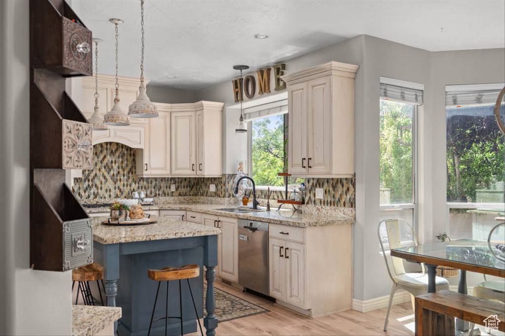 Kitchen with appliances with stainless steel finishes, backsplash, light wood-style floors, and light stone counters