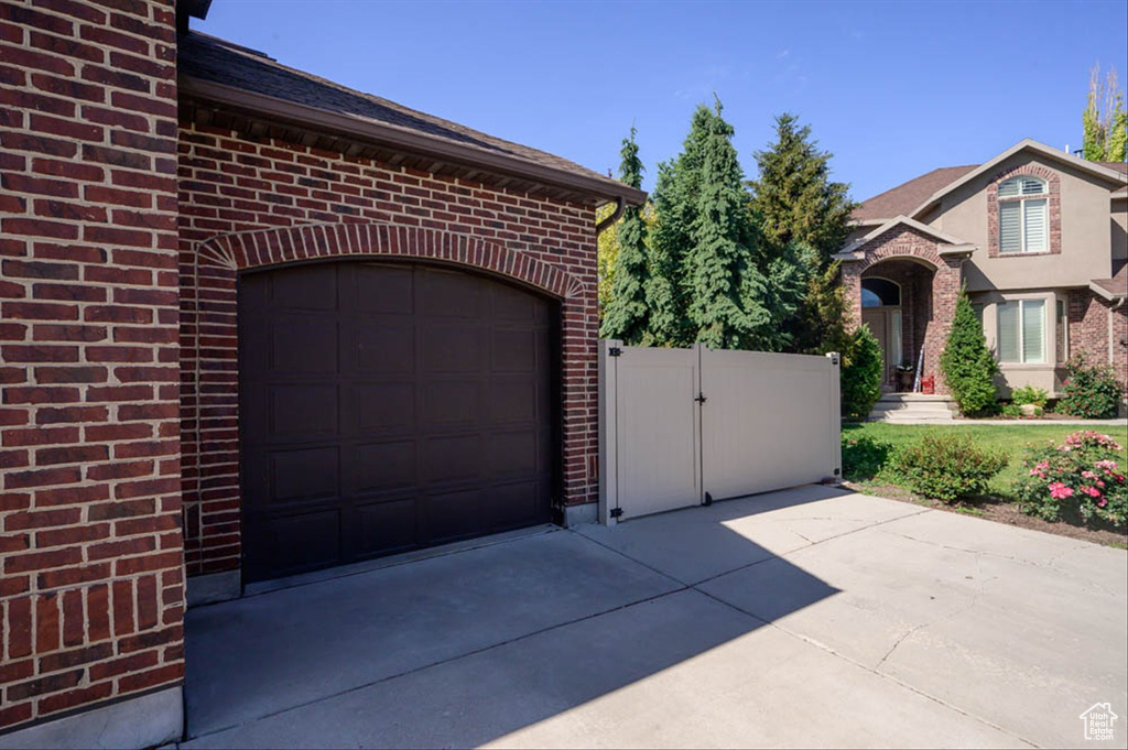 Garage featuring driveway and a gate