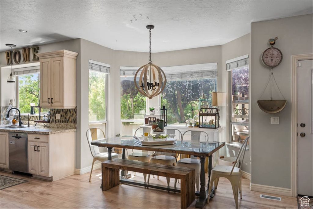Dining room featuring a chandelier, light wood-style floors, and a textured ceiling