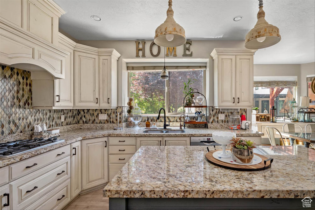 Kitchen with cream cabinets, healthy amount of natural light, light stone counters, decorative backsplash, and recessed lighting