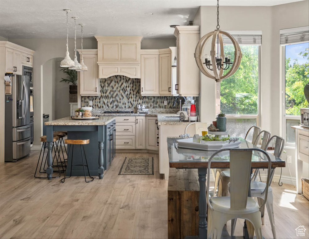 Kitchen featuring appliances with stainless steel finishes, a chandelier, a breakfast bar, and light wood finished floors