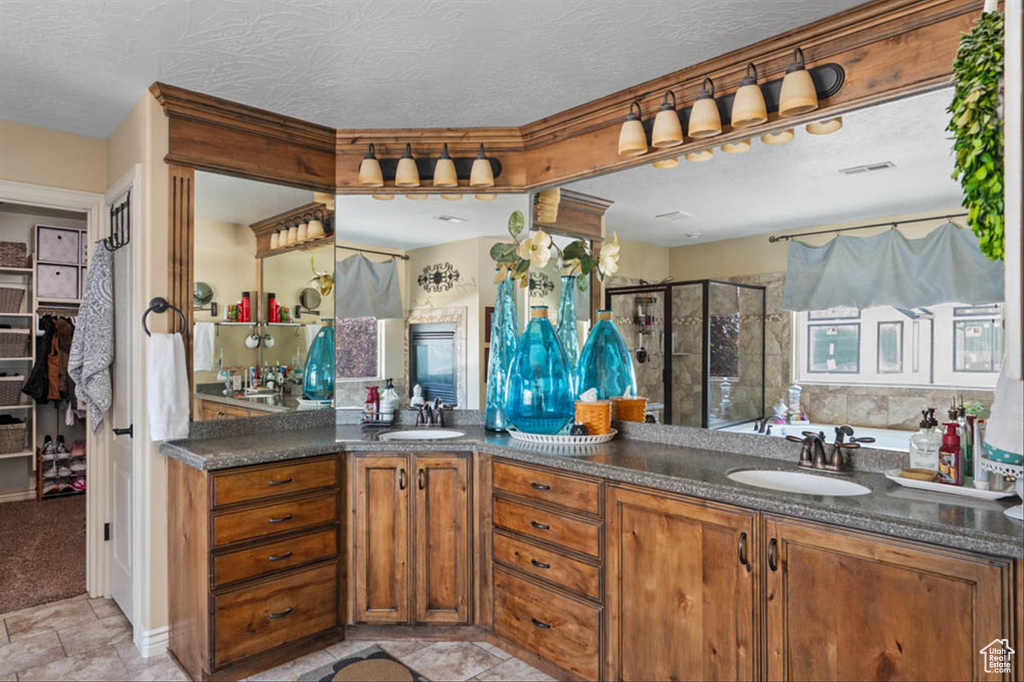 Full bathroom with a stall shower, double vanity, and a textured ceiling