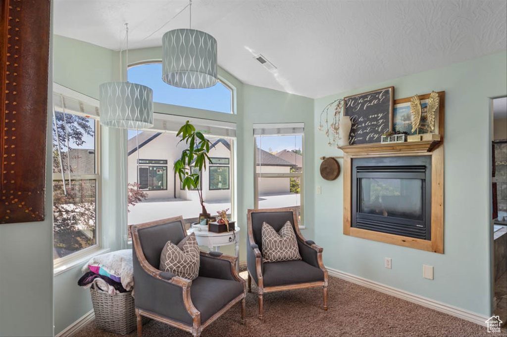 Sitting room with lofted ceiling, carpet floors, and a glass covered fireplace