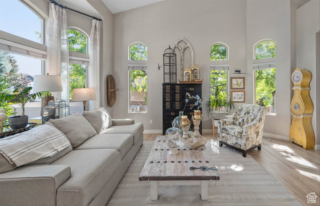 Living area featuring healthy amount of natural light, light wood-style flooring, and a high ceiling