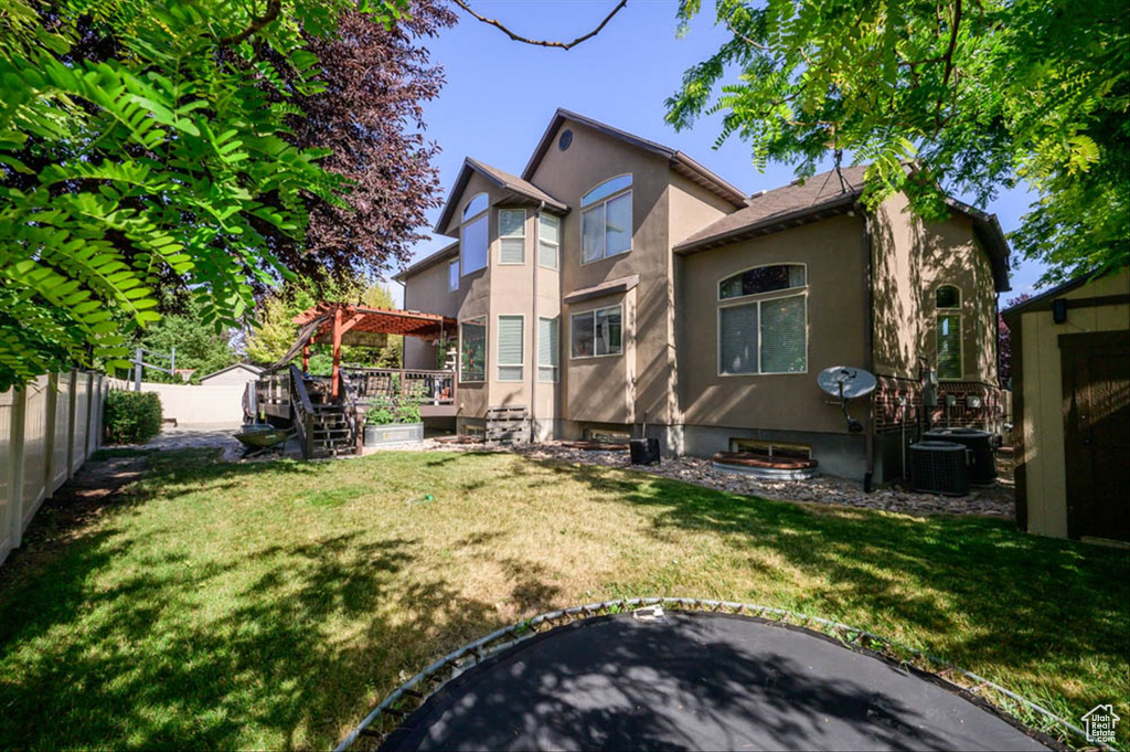 Back of property featuring stucco siding, a fenced backyard, a pergola, and a deck