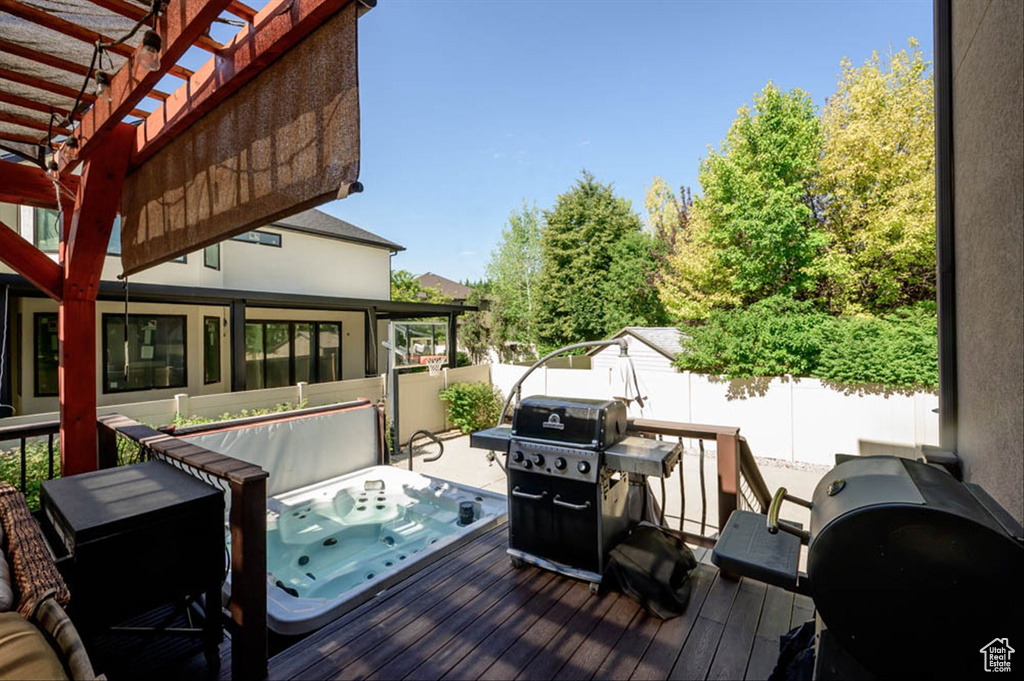 Deck with a grill, a fenced backyard, a covered hot tub, and a pergola
