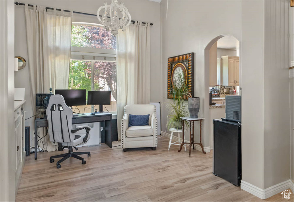 Office with arched walkways, light wood-style flooring, and a chandelier