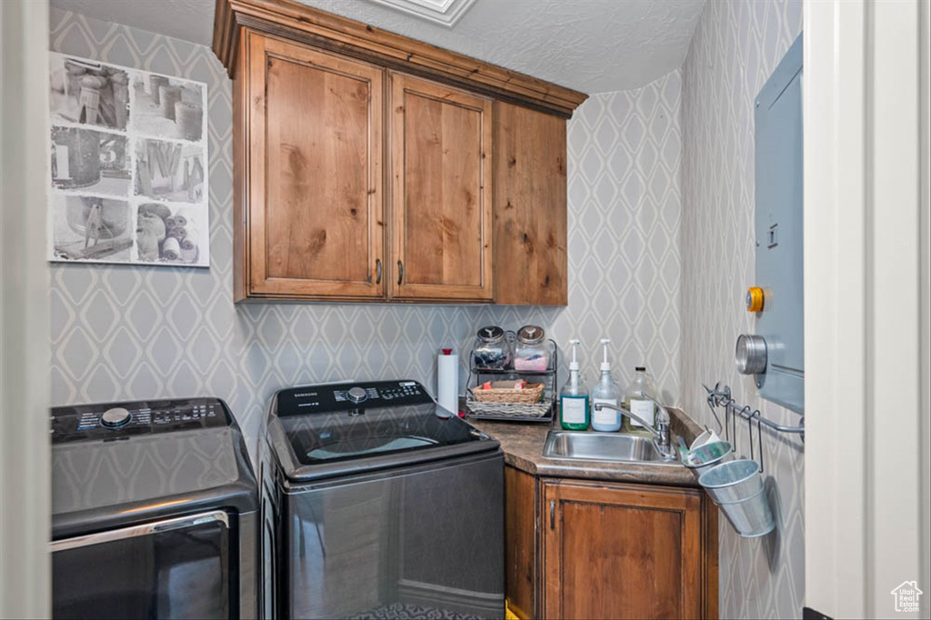 Laundry room with wallpapered walls, cabinet space, and separate washer and dryer