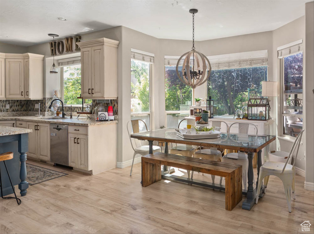 Kitchen featuring dishwasher, a chandelier, light wood-style floors, tasteful backsplash, and light stone counters